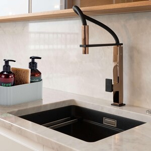 Moderner Spülbecken Organizer in Hellgrau, der mittels neustem 3D Druck in Deutschland gefertigt wird. Der Spül Organizer ist im Scandi Stil gehalten. Er ist minimalistisch designt und hat eine feine Rillenstruktur. Der Design Organizer ist befüllt mit Handseife, Spülschwamm sowie Spülmittel. Der stylische Küchen Organizer steht in einer modernen aufgeräumten Küche auf einer Marmorarbeitsplatte neben einem schwarzen Spülbecken mit Messing Wasserhahn. Utensilienhalter für Ordnung in der Küche.