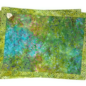 Op de afbeelding: Set van twee groene placemats met een groen en blauw bloemenpatroon en een zwarte stippenrand.