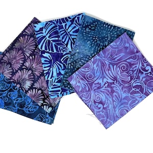 Könnte beinhalten: Fünf Stoffquadrate in Blautönen und Lila mit verschiedenen Batik-Mustern. Die Muster umfassen Blätter, Wirbel und florale Designs.