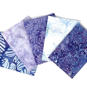 Può includere: Cinque quadrati di tessuto in tonalità di blu e viola con diversi motivi batik. I motivi includono foglie, vortici e disegni astratti.