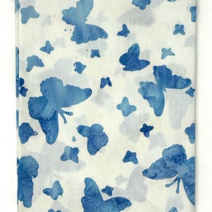 Könnte beinhalten: Weißer Stoff mit einem blauen Schmetterlingsmuster. Der Stoff trägt den Aufdruck "Batik-120".
