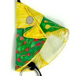 Pode incluir: Um chaveiro de tecido colorido com um design estampado em verde, amarelo e vermelho. O chaveiro tem um anel prateado e um tassel vermelho.