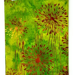 Op de afbeelding: Groene stof met een batik-ontwerp met bruine paardenbloem-achtige bloemen. De stof heeft de tekst "Batik-114" erop gedrukt.