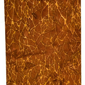 Könnte beinhalten: Ein brauner Stoff mit einem Batik-Muster aus einem hellbraunen, komplizierten, netzartigen Design. Der Stoff hat ein Etikett mit der Aufschrift "Batik-118".