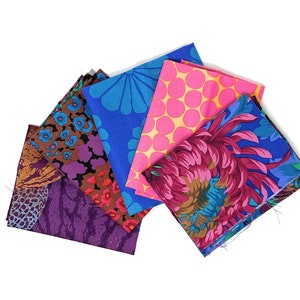 Könnte beinhalten: Ein Stapel aus sechs bunten Stoffquadraten mit verschiedenen Mustern, darunter Blumen-, geometrische und Tiermuster. Die Stoffe sind in den Farben Rosa, Blau, Lila und Braun.