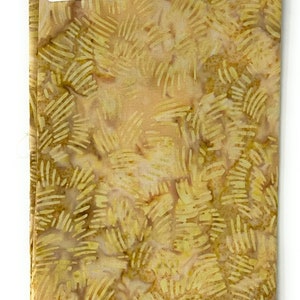 Könnte beinhalten: Ein beigefarbener Stoff mit einem Batik-Muster aus gelben Linien und Wirbeln. Der Stoff hat ein Etikett mit der Aufschrift "Batik-104".