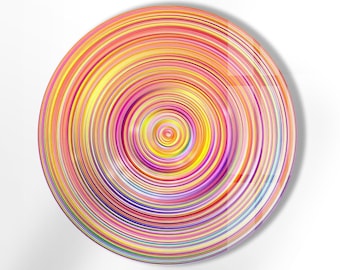 Könnte beinhalten: Ein farbenfrohes kreisförmiges Design mit konzentrischen Kreisen in Rot, Orange, Gelb, Grün, Blau, Lila und Rosa.