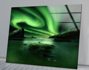 May include: A vibrant green aurora borealis, also known as the Northern Lights, illuminates the night sky over a rocky coastline. The green light reflects off the calm water, creating a magical and ethereal scene.