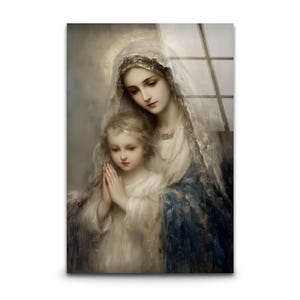 Op de afbeelding: Een religieus kunstwerk met een vrouw en een kind. De vrouw draagt een witte sluier en een blauwe jurk, het kind is in het wit gekleed. De handen van het kind zijn gevouwen in gebed. Het kunstwerk heeft een zachte, schilderachtige stijl.