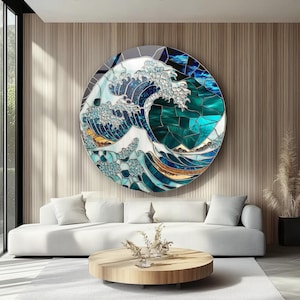 Op de afbeelding: Een rond glas-in-lood kunstwerk dat een gestileerde oceaangolf in tinten blauw, teal en wit afbeeldt. Het kunstwerk is gemonteerd op een houten muur boven een witte bank. Het golfontwerp doet denken aan Japanse kunst.