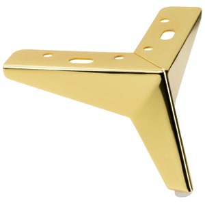 May include: Gold metal furniture leg with a triangular shape and a round plastic foot pad. The leg has several holes for mounting.