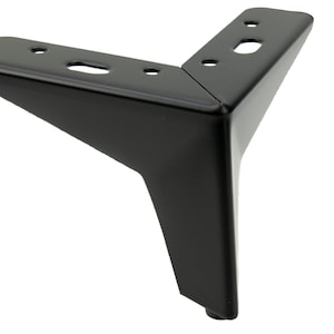 Pode incluir: Pernas de mobiliário em metal preto com forma triangular e cinco furos para parafusos. A perna tem uma parte inferior arredondada.