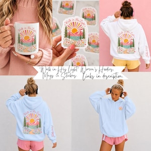 May include: A white ceramic mug, a die-cut sticker, and white and light blue hooded sweatshirts, all featuring a graphic of a sun, mountains, pine trees, and a path with the text Walk in His Light and John 8:12 on the sleeve.