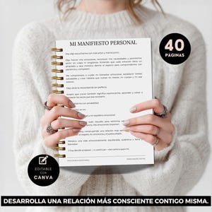May include: A spiral-bound notebook with gold-colored metal rings, held by a person. The notebook's cover reads "MI MANIFIESTO PERSONAL" in Spanish. The notebook has 40 pages and is editable with Canva. The bottom text reads "DESARROLLA UNA RELACI&Oacute;N M&Aacute;S CONSCIENTE CONTIGO MISMA."