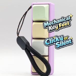 Peut inclure: Un jouet anti-stress violet avec quatre boutons carrés de couleurs pastel : vert, jaune, gris et beige. Il possède une dragonne noire et le texte "Mechanical Key Feel" et "Clicky or Silent".