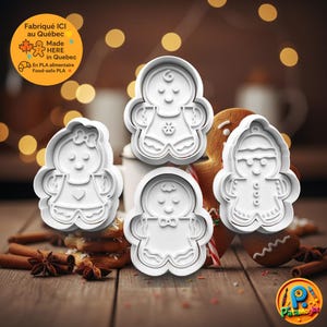 Puede incluir: Cortadores de galletas de jengibre de plástico blanco en varios diseños, incluyendo un hombre de jengibre, una mujer y un niño. Los cortadores se muestran sobre una superficie de madera con una galleta de jengibre en el fondo. El texto "Made HERE in Quebec" es visible.