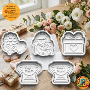 May include: A collection of white plastic cookie cutters in various shapes, including a flower heart, a mother and child, a gift box with a heart, and two trophies that say "BEST MOM". The image also includes flowers and soap.