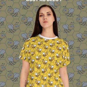 Op de afbeelding: Gele pyjamashortset met een bijenpatroon. De top heeft een witte rand rond de halslijn. De achtergrond heeft een herhalend patroon van bijen en honingraatvormen. Tekst op de afbeelding luidt "PAJAMA SHORT SET" en "BUSY AS BEES 1".