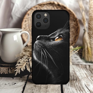 May include: Black phone case with a close-up image of a black cat looking up with one bright yellow eye.
