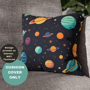 May include: A decorative cushion cover featuring a space-themed design. The dark blue cover is printed with colorful planets, stars, and the text "Design printed on Canvas. NOT Textured" and "CUSHION COVER ONLY". The cushion is resting on a gray sofa.