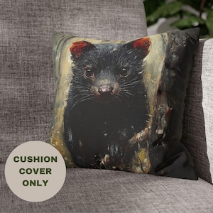 May include: A black and white cushion cover with a close-up image of a Tasmanian devil. The devil is looking directly at the viewer with its mouth closed. The background is a blurred image of a tree trunk.