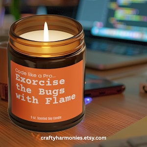May include: A lit, scented soy candle in a brown glass jar with a gold rim. The orange label reads "Code like a Pro... Exorcise the Bugs with Flame." The candle is 255 grams and has the Etsy shop URL at the bottom.