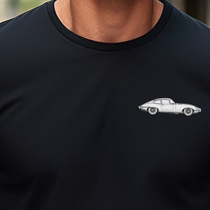 Puede incluir: Camiseta negra de cuello redondo con un pequeño gráfico de coche blanco en el pecho. El coche es un diseño de coupé clásico con detalles precisos. La camiseta está hecha de una tela suave y oscura.