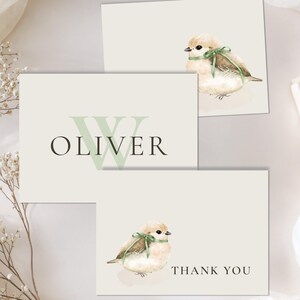 May include: Stationery set featuring three cards with a watercolor bird design and the name "Oliver". One card reads "Thank You". The bird has a green ribbon. A wrapped gift box with a ribbon is also present.