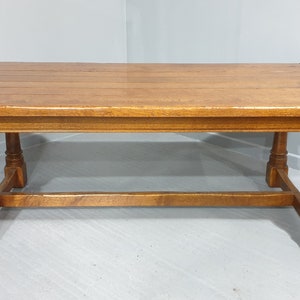May include: A solid wood dining table with a rectangular top and turned legs. The table has a simple, rustic design and is made of a dark brown wood.