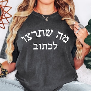 May include: A dark gray t-shirt with white text that reads "Ma Shelanu Lekhaim" in Hebrew.