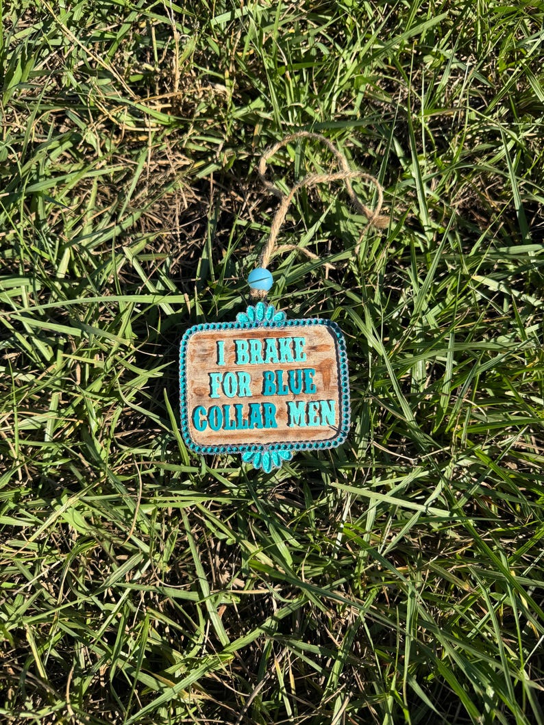 K&ouml;nnte beinhalten: Ein Holzschild mit blauen und wei&szlig;en Akzenten tr&auml;gt die Aufschrift "I Brake For Blue Collar Men".