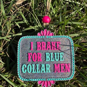 K&ouml;nnte beinhalten: Ein silbernes Glitzer-Schild mit t&uuml;rkisfarbenem Rand und rosa Blumen. Das Schild lautet "I Brake For Blue Collar Men".