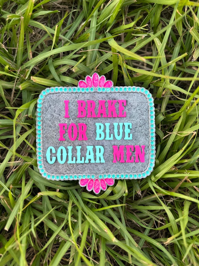 K&ouml;nnte beinhalten: Eine graue G&uuml;rtelschnalle aus Metall mit einem t&uuml;rkisfarbenen und rosafarbenen Rand. Die Schnalle tr&auml;gt den Text "I Brake For Blue Collar Men" in rosa und t&uuml;rkisfarbener Schrift.