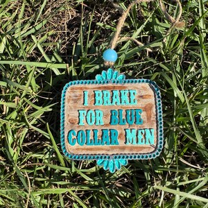 K&ouml;nnte beinhalten: Ein Holzschild mit t&uuml;rkisfarbenem Rand und Strasssteinen. Das Schild tr&auml;gt die Aufschrift "I Brake For Blue Collar Men".