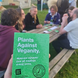 Puede incluir: Una caja de juego de cartas verde con el t&iacute;tulo "Plants Against Veganity." La caja tiene un fondo verde con texto blanco y una marca de verificaci&oacute;n en un c&iacute;rculo que dice "Tambi&eacute;n adecuado para no veganos." El texto en la caja dice "Making Vegans Fun at Parties Since 2024."