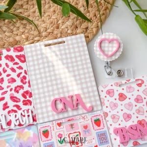 May include: A collection of badge holders and accessories. The badge holders feature various patterns, including a pink and white gingham, a pink leopard print, and a pattern of hearts and gifts. The word "CNA" is displayed in pink letters on one badge holder.