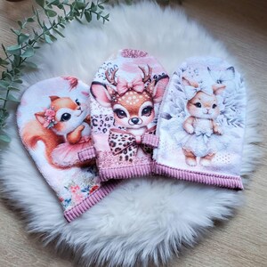 Peut inclure: Trois débarbouillettes en forme de cœur avec des motifs d'animaux. L'une représente un renard en tutu rose, une autre un cerf avec un nœud léopard et la troisième un lapin en robe. Chacune a une bordure côtelée rose et est posée sur une surface blanche et moelleuse.