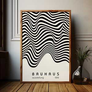 May include: A black and white abstract art print with wavy lines. The print is framed in a natural wood frame and has the text "BAUHAUS ausstellung 1919" at the bottom.