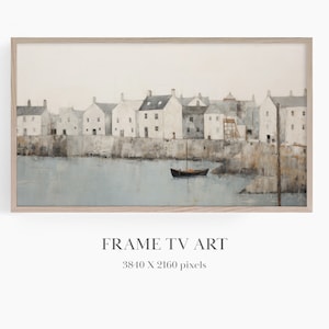May include: A painting of a small town with white houses along a waterfront. A small boat is in the water in front of the town. The painting is in a light wood frame.