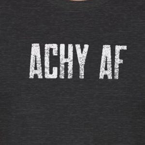 Puede incluir: Una camiseta gris oscura con el texto "Achy AF" impreso en blanco.