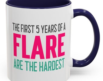May include: White ceramic coffee mug with a navy blue rim and handle. The mug has the text "The first 5 years of a FLARE are the hardest" printed on it. The word "FLARE" is in pink and the rest of the text is in black and green.