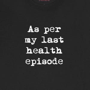 May include: Black t-shirt with white text that reads "As per my last health episode." The text is in a typewriter font. The top of the shirt has the text "Is killing me."