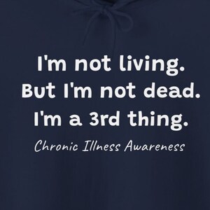 May include: Navy blue hooded sweatshirt with white text that reads "I'm not living. But I'm not dead. I'm a 3rd thing. Chronic Illness Awareness."