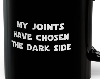 May include: Black coffee mug with white text that reads "My joints have chosen the dark side."