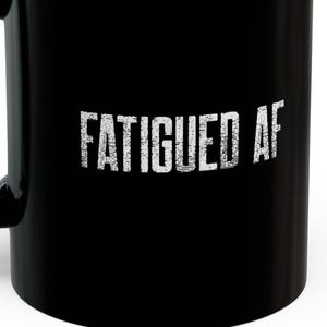 Könnte beinhalten: Schwarze Kaffeetasse mit weißem Text, der "FATIGUED AF" lautet.