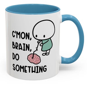 May include: White ceramic mug with a blue rim and handle. The mug features a cartoon illustration of a stick figure prodding a brain with a stick. The text on the mug reads "C'mon, brain, do something."