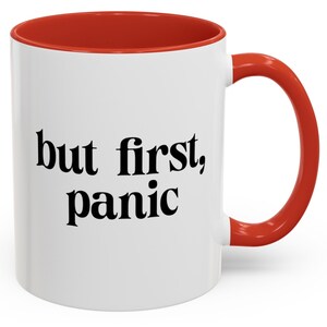 Può includere: Tazza in ceramica bianca con interno e manico rossi. La tazza presenta la frase "but first, panic" in nero, a caratteri grassi. Un oggetto umoristico e pratico per gustare bevande.