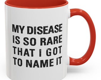May include: White coffee mug with a red rim and handle. The mug has black text that reads "My disease is so rare that I got to name it."