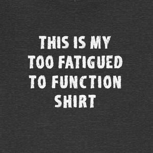 Op de afbeelding: Zwart T-shirt met witte tekst die "This is my too fatigued to function shirt." luidt.