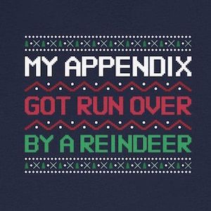 Könnte beinhalten: Marineblaues T-Shirt mit dem Text "MY APPENDIX GOT RUN OVER BY A REINDEER" im pixeligen Ugly-Christmas-Sweater-Stil. Das Design umfasst grüne Bäume und rote und weiße Akzente.